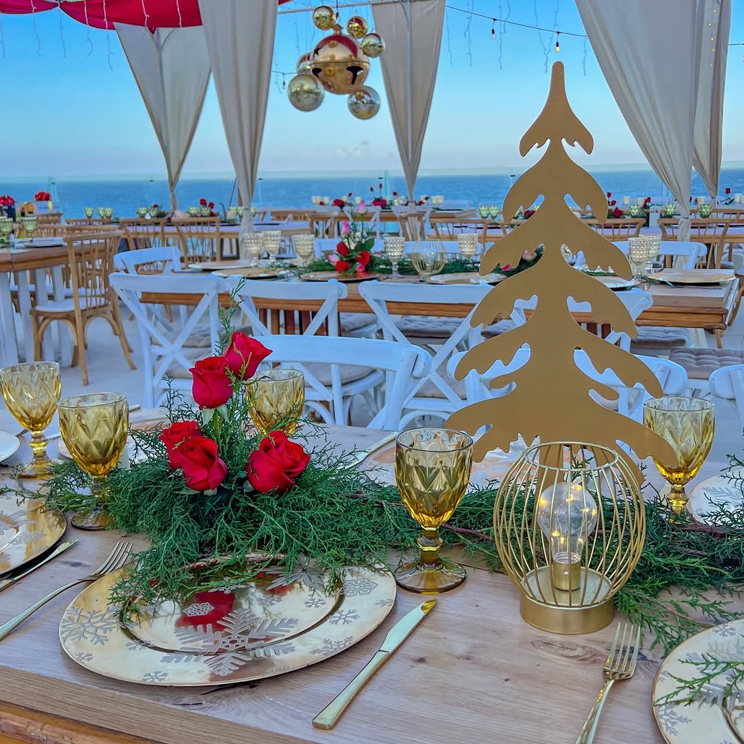 Recepción elegante frente al mar con mesas largas y cristalería ámbar